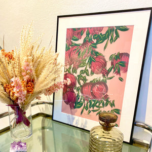 affiche grenade format 40 x 50 cm décorant un salon, accompagné d'un bouquet de fleurs séchées rose et d'un flacon vintage de couleur brun fumé.