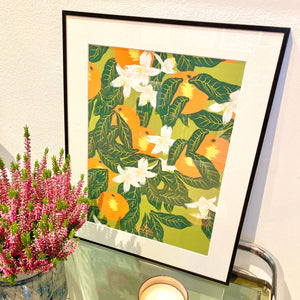 affiche d'oranger en fleurs et oranges format 40 x 50 cm décorant un salon, accompagné d'un bouquet de bruyere rose et d'une bougie apothéca. 